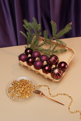 Cardboard egg tray with baubles, Christmas tree branch and a plate with gold beads. Creative new year's still life