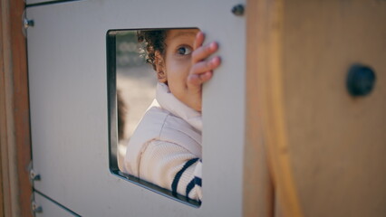 Fototapeta na wymiar African american kid playing in toy house closeup. Cute girl looking from window