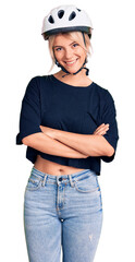 Young beautiful blonde woman wearing bike helmet happy face smiling with crossed arms looking at the camera. positive person.