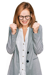 Young caucasian woman wearing business style and glasses excited for success with arms raised and eyes closed celebrating victory smiling. winner concept.