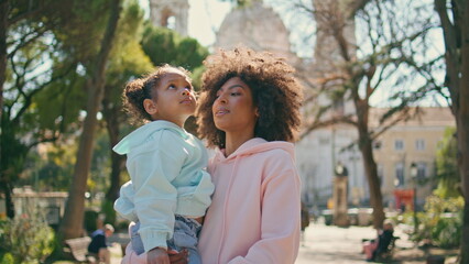 Fototapeta premium Mother daughter watching park beauty standing at alley close up. African family
