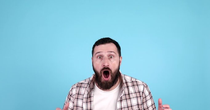 Amazed excited bearded man doesn`t believe his success, keeps hands on head, stares at camera, says omg or wow. 