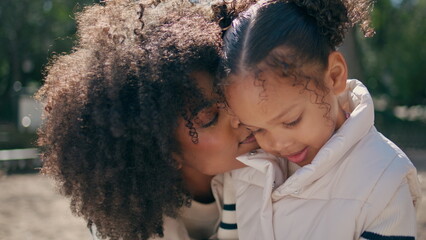 Mother expressing love to daughter having fun together on sunny nature close up.