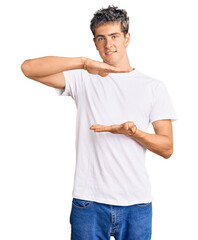 Young handsome man wearing casual white tshirt gesturing with hands showing big and large size sign, measure symbol. smiling looking at the camera. measuring concept.