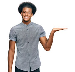 African american man with afro hair wearing casual clothes smiling cheerful presenting and pointing with palm of hand looking at the camera.