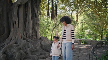 Woman daughter strolling park sunny day. African american mother girl walking 