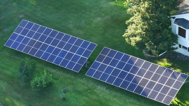 Private home with solar photovoltaic panels mounted on stand-alone frame on backyard ground for generating of clean ecological electric energy in suburban rural town area. Concept of autonomous house