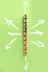 Banner with wooden cubes, text START 2024 and drawn arrows on green background