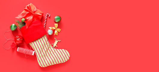 Beautiful Christmas sock with gift and decorations on red background with space for text