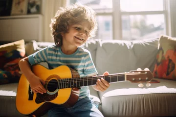Fotobehang Cute little boy learning to play guitar in living room. Child having fun with music instrument. Art education for kids. © MNStudio