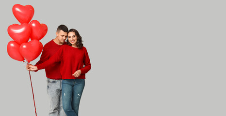 Loving young couple with heart-shaped balloons on grey background with space for text. Valentine's...