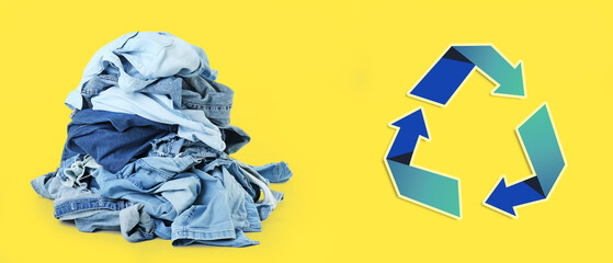 Heap of clothes and recycling symbol on yellow background. Ecology concept