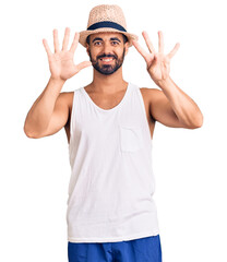 Fototapeta premium Young hispanic man wearing casual summer hat showing and pointing up with fingers number nine while smiling confident and happy.
