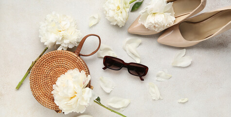 Composition with female sunglasses, handbag, high heels shoes and beautiful peony flowers on light grunge background