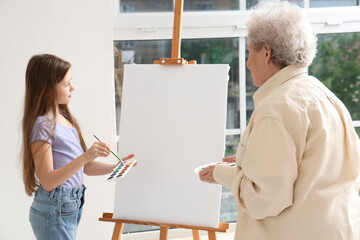 Little girl with her grandmother drawing at home