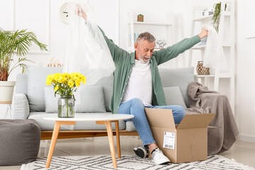 Shocked mature man unpacking parcel at home