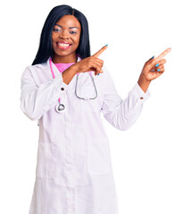 Young african american woman wearing doctor stethoscope smiling and looking at the camera pointing...