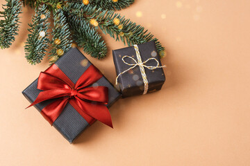 Gift boxes with red bow and fir branches on neutral beige background. Top view, flat lay, copy space