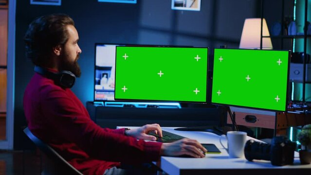 Photo editor using green screen monitor to color correct photographs in creative studio. Photographer selecting best pictures for editorial content with chroma key desktop computer