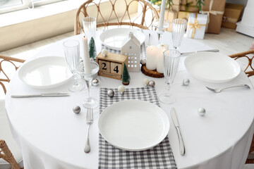 Festive table setting with burning candles and Christmas decor