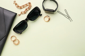 Composition with stylish sunglasses, modern smartwatch and female accessories on green background