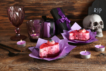 Delicious fruit cakes, burning candles, skull and glasses for Halloween celebration on wooden background, closeup