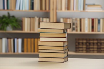 Stack of books on wooden table in library