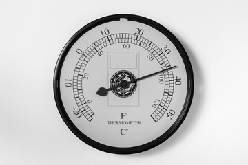 Termómetro analógico circular marcando 36 grados celcius, aislado en blanco