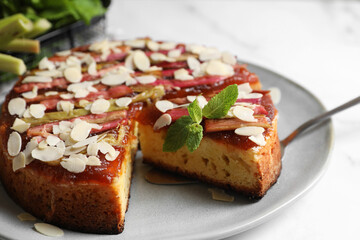 Freshly baked rhubarb pie with almond flakes and cake server on white table, closeup
