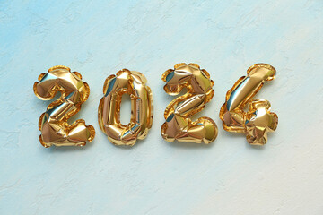 Golden figure 2024 made of balloons for Christmas celebration on light background