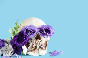 Human skull with beautiful flowers on blue background