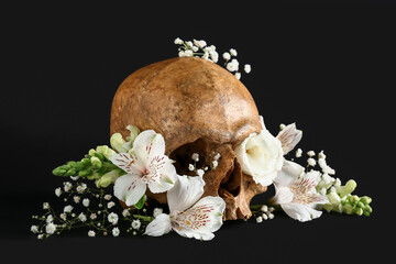 Human skull with beautiful lily and gypsophila flowers on black background