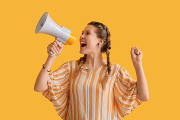 Young woman shouting into megaphone on yellow background