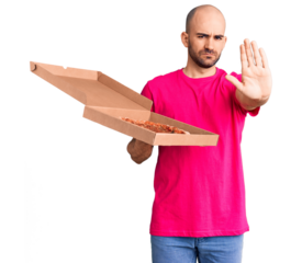 Young handsome man holding delivery pizza cardboard box with open hand doing stop sign with serious and confident expression, defense gesture
