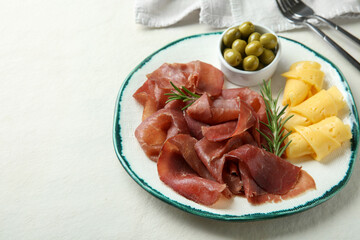 Delicious bresaola, cheese, olives and rosemary on light textured table. Space for text