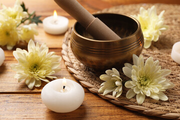 Tibetan singing bowl with mallet, beautiful chrysanthemum flowers and burning candles on wooden...