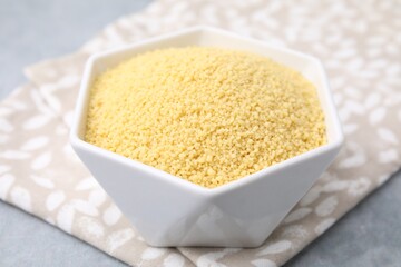 Raw couscous in bowl on table, closeup