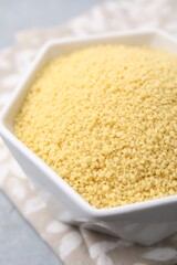 Raw couscous in bowl on table, closeup