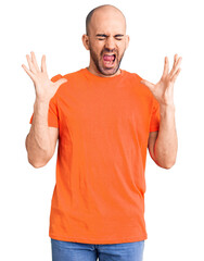 Young handsome man wering casual t shirt celebrating mad and crazy for success with arms raised and...