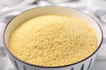 Raw couscous in bowl on table, closeup
