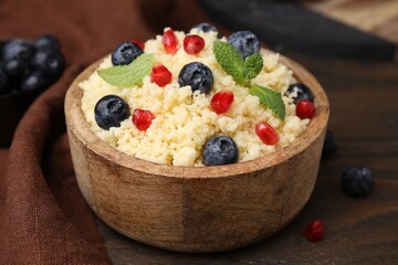 Bowl of tasty couscous with blueberries, pomegranate and mint on table, closeup
