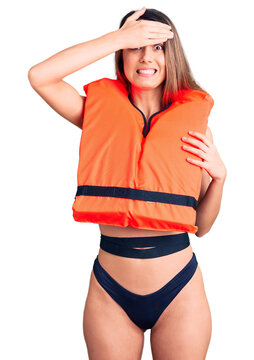Young beautiful girl wearing life jacket stressed and frustrated with hand on head, surprised and angry face