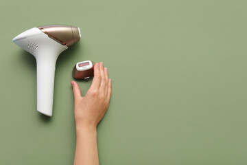 Female hands with modern photoepilator attachment on green background
