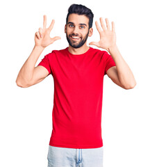 Young handsome man with beard wearing casual t-shirt showing and pointing up with fingers number eight while smiling confident and happy.