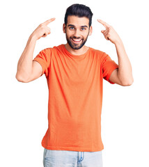 Young handsome man with beard wearing casual t-shirt smiling pointing to head with both hands finger, great idea or thought, good memory