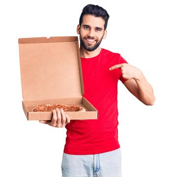 Young handsome man with beard holding delivery cardboard with italian pizza pointing finger to one self smiling happy and proud