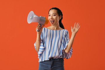 Young Asian woman with megaphone on orange background