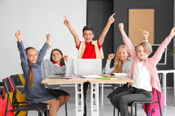 Happy little children studying at school computer lab