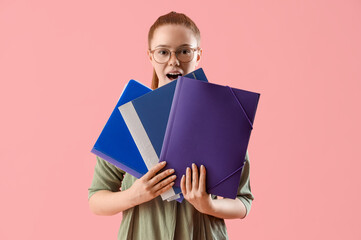 Surprised young woman with document folders on pink background