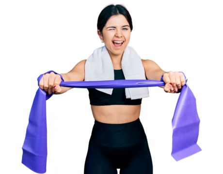 Young brunette woman with blue eyes training arm resistance with elastic arm bands winking looking at the camera with sexy expression, cheerful and happy face.